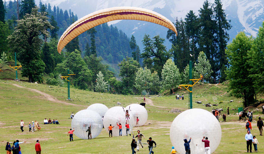 People joyfully playing with large balloons and parachutes in Manali, creating a festive and lively atmosphere.