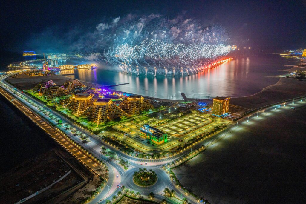 An aerial view of Ras Al Khaimah at night, with lit-up roads, fireworks, and rivers